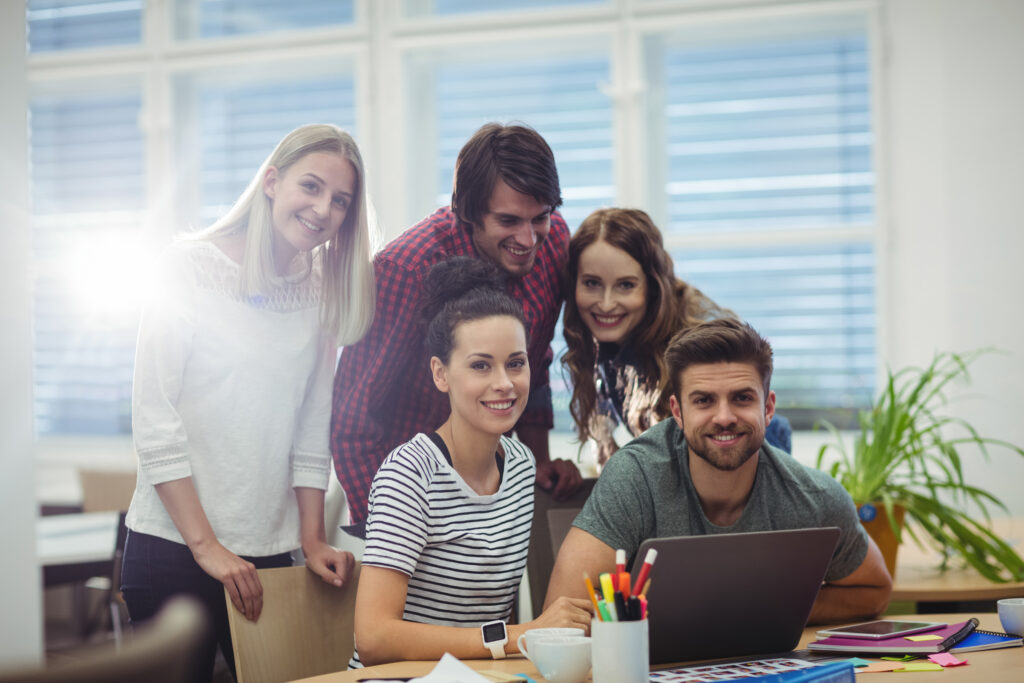 group of business executives smiling at camera at their desk